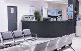 Clinical reception with waiting room in facility lobby, registration counter used for patients with medical appointments. Empty reception desk in health center for checkup visits.